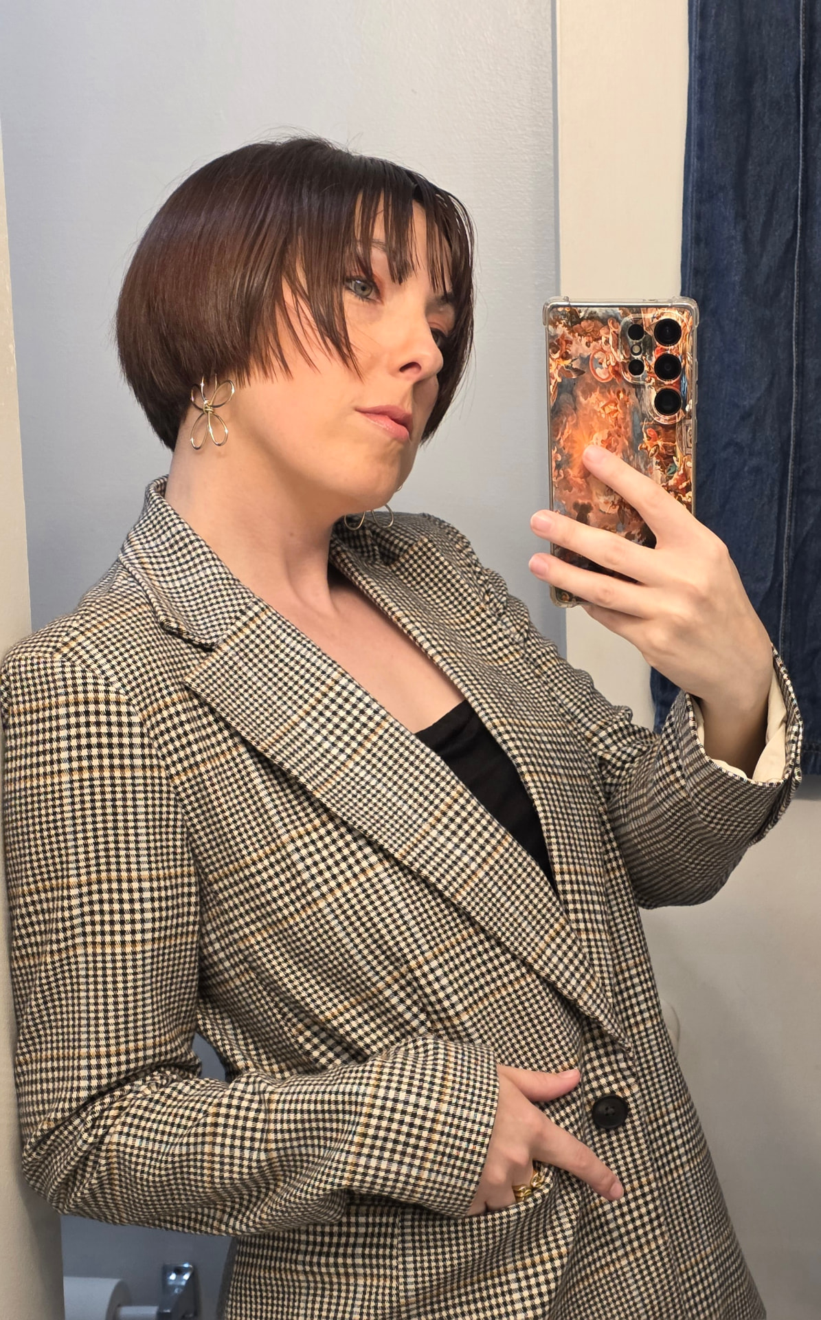 Abi in a houndstooth blazer taking a mirror selfie